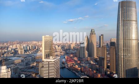 Un paesaggio urbano di Tianjin, Cina con grattacieli e un fiume sotto la luce del sole Foto Stock