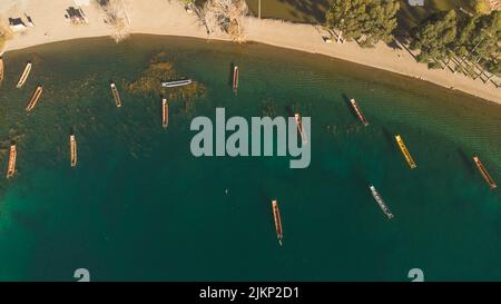 Una vista aerea dall'alto di piccole barche in legno su un verde corpo d'acqua vicino alla riva al sole Foto Stock