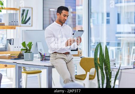 Im sempre alla ricerca di nuove innovazioni. Un uomo d'affari che utilizza un tablet digitale in un ufficio moderno. Foto Stock