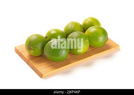 Un primo piano di lime su una tavola di legno isolata su uno sfondo bianco Foto Stock