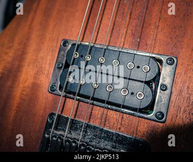 Un primo piano delle corde di una chitarra elettrica in legno Foto Stock