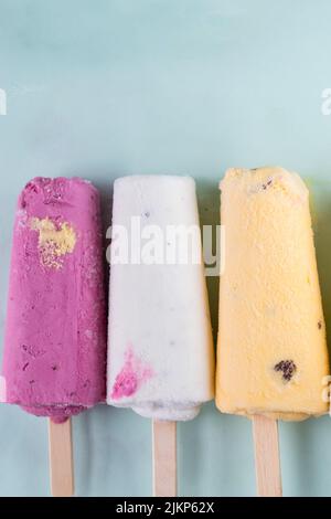 Uno shot verticale di tre gelati con frutta e bacche in tre colori sul tavolo Foto Stock