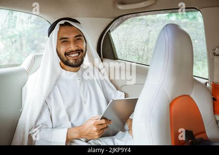 uomo che indossa il turbante usando un tampone mentre si siede sulla sua auto Foto Stock
