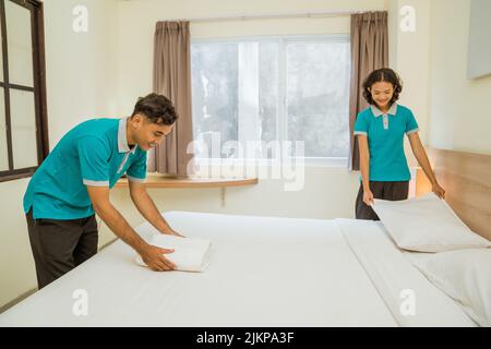 pulitori maschili e femminili che indossano uniformi che fanno i letti Foto Stock