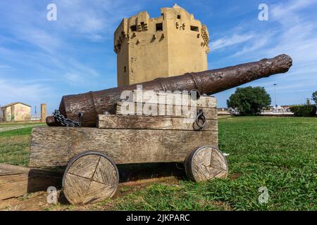 Un primo piano di un vecchio cannone su una carrozza lignea contro la torre aragonese Foto Stock