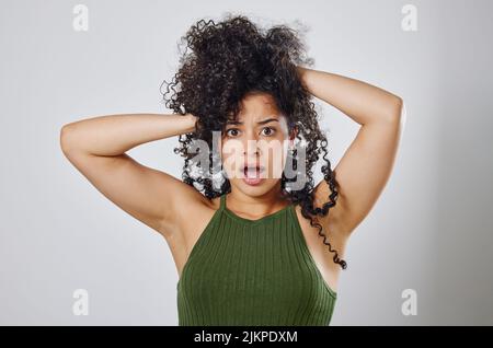 Che cosa hai appena detto dei miei capelli. Studio girato di una donna con capelli disordinati posando su uno sfondo grigio. Foto Stock