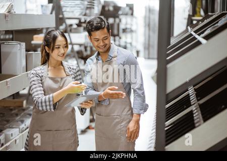 Ragazzo e ragazza che indossano grembiuli usando l'imbottitura durante il controllo degli oggetti Foto Stock