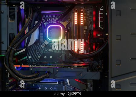 Primo piano e all'interno di PC desktop ad alte prestazioni e sistema di raffreddamento su socket CPU con LED RGB multicolore indicano lo stato di funzionamento Foto Stock