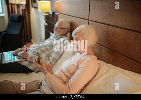 Coppia anziana che si trova a letto e guarda qualcosa online Foto Stock