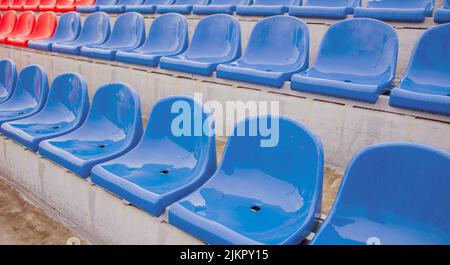 Vuoto bleacher nello stadio sportivo in tempo piovoso. Sedili colorati bagnati nello stadio di strada. Piove. Primo piano Foto Stock