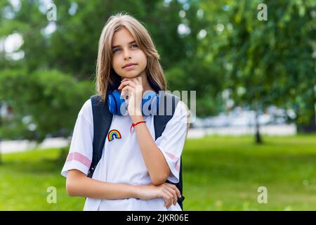 ragazza in età adolescente con zaino e cuffia nel concetto di ritorno a scuola parco Foto Stock