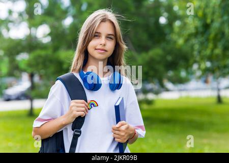 ragazza in età adolescente con zaino e cuffia nel concetto di ritorno a scuola parco Foto Stock