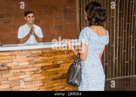 l'addetto alla reception sorride con un gesto di benvenuto quando arriva l'ospite Foto Stock