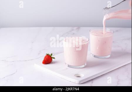 Versando kefir di frutta fatta in casa, latticello o yogurt con probiotici. Foto Stock