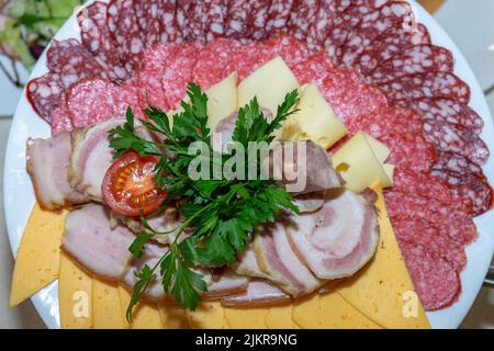 Un piatto di antipasti freddi con varie salsicce, carne e formaggio. Verdi e pomodori. Foto Stock