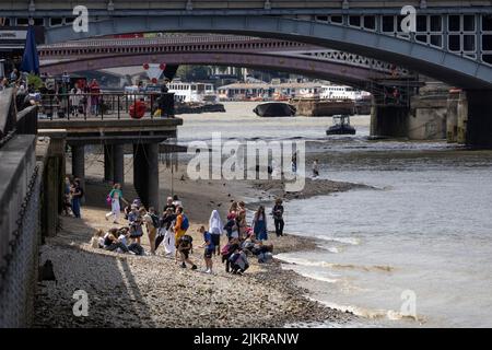 Grandi distese di rocce, ciottoli e spiagge sabbiose di bijou sono esposte sul Tamigi, mentre la gente sta allagando fango con la bassa marea, Londra, Regno Unito Foto Stock