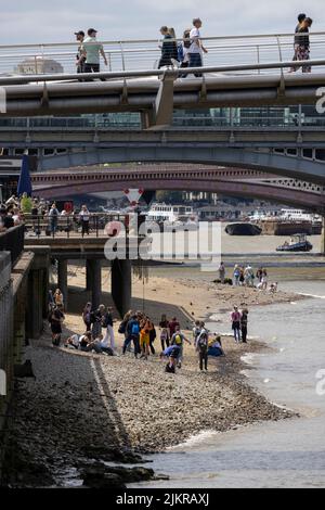 Grandi distese di rocce, ciottoli e spiagge sabbiose di bijou sono esposte sul Tamigi, mentre la gente sta allagando fango con la bassa marea, Londra, Regno Unito Foto Stock