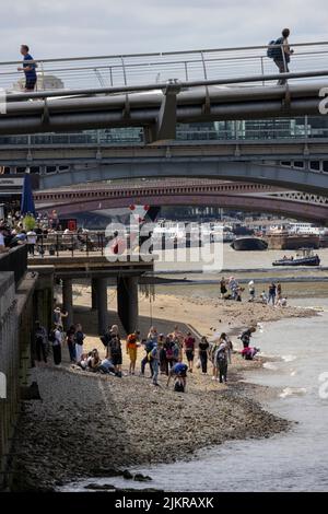 Grandi distese di rocce, ciottoli e spiagge sabbiose di bijou sono esposte sul Tamigi, mentre la gente sta allagando fango con la bassa marea, Londra, Regno Unito Foto Stock