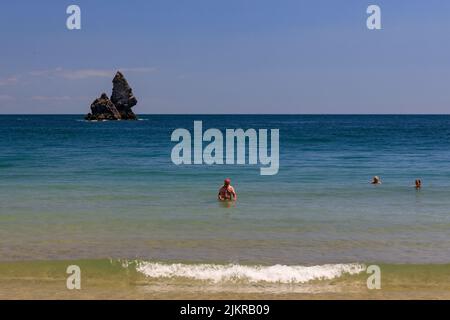 Nuotatori a Broadhaven Beach con Church Rock Beyond, Pembrokeshire, Galles, Regno Unito Foto Stock