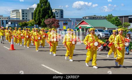 I membri di Falun Dafa, o Falun Gong, un movimento religioso cinese, marciando e suonando tamburi della vita a Rotorua, Nuova Zelanda Foto Stock