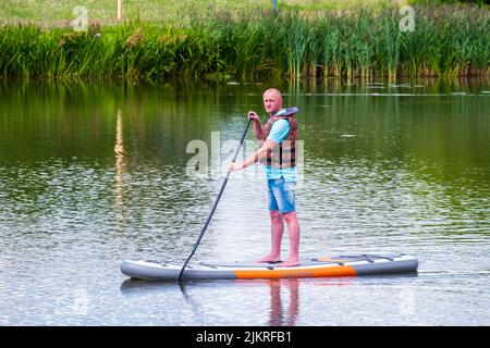 L'uomo su una tavola da paddle Stand Up nuota lungo il fiume Svisloch. Vacanze estive Foto Stock