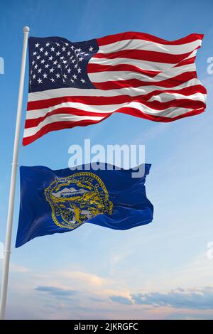 Grande bandiera ufficiale degli Stati Uniti d'America con bandiera più piccola dello stato del Nebraska, Stati Uniti d'America su sfondo cielo nuvoloso. Stati Uniti d'America concetto patriottico. Spazio copia per Foto Stock