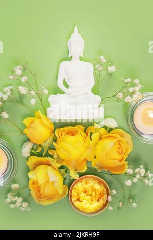 Statua del Buddha, rose gialle e candele su sfondo verde. Magha Puja, Asalha Puja, Vesak Puja Day, concetto di vacanza buddista. Immagine soft e soft Foto Stock