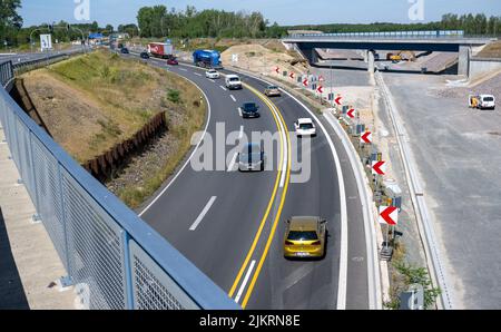 03 agosto 2022, Sassonia, Rötha: I veicoli lasciano la superstrada A72 vicino a Rötha, proprio accanto al cantiere per l'ultima sezione della superstrada. Mentre l'espansione dell'ultima sezione del A72 continua, il B95 intorno Espenhain è in fase di smantellamento. Un percorso ciclabile è attualmente in costruzione tra Borna e Rötha, utilizzando in gran parte le corsie esistenti del vecchio B95 come base. I lavori sul pezzo centrale continueranno fino a metà ottobre. Poi l'ex autostrada federale molto trafficata diventerà strada statale 242 con fiancheggianti strisce verdi e spazio per pedoni e ciclisti. Foto: Hendrik Schmidt/dpa Foto Stock