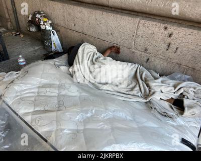 L'uomo dorme su un materasso sul marciapiede nel mezzo di Manhattan, New York City. Foto Stock