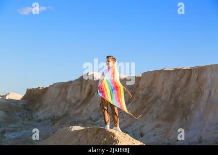 Un ragazzo con un aquilone si alza su una montagna e guarda in lontananza. Il concetto di libertà e fantasia. Foto Stock