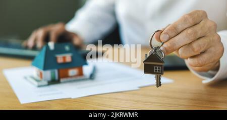 agente immobiliare che dà nuove chiavi di casa al cliente dopo che il contratto è completo. banner con spazio di copia Foto Stock
