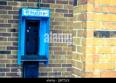 Telefono a pagamento abbandonato vuoto contro muro di mattoni Foto Stock