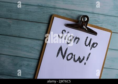 Top view image of paper clipboard with text Iscriviti ora! Foto Stock