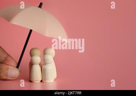 Ombrello e bambole in legno con spazio copia. Concetto di protezione della famiglia e copertura assicurativa. Foto Stock