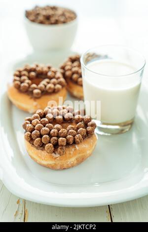 Un colpo verticale di ciambelle di cereali al cioccolato e una tazza di latte Foto Stock