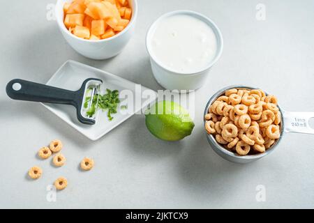 Un primo piano di cheerios, yogurt, frutta e lime isolato su uno sfondo bianco Foto Stock