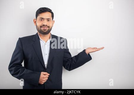 sorridente uomo d'affari indiano mostrando mano vuota palma per prodotto immaginario per annunci visivi o pubblicità Foto Stock
