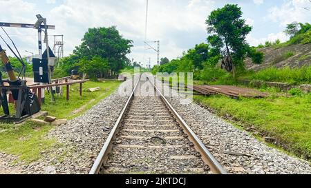 Un primo piano di ciottoli sulla ferrovia circondata dal verde in una giornata nuvolosa Foto Stock