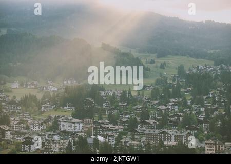 Un bellissimo scatto di una città situata su un campo circondato da alberi in tempo nebbiosa. Foto Stock