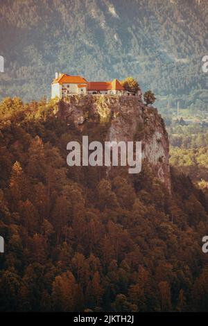 Uno scatto verticale di alcune case poste su una scogliera circondata da alberi sullo sfondo delle montagne. Foto Stock