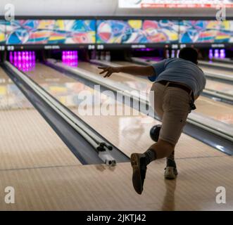 Un primo piano di un giovane che gioca a bowling Foto Stock