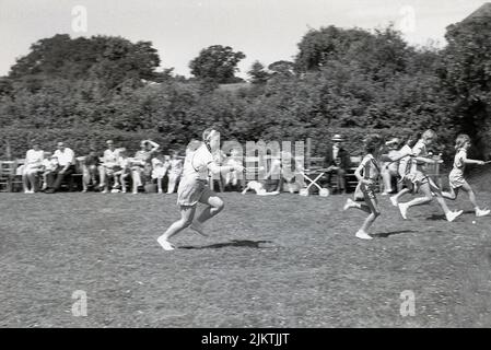 1960, storico, ora estiva e fuori in un campo, giovani ragazze che competono in una gara di uovo-e-cucchiaio, una tradizionale attività sportiva nelle giornate di sport della scuola primaria, Inghilterra, Regno Unito Foto Stock