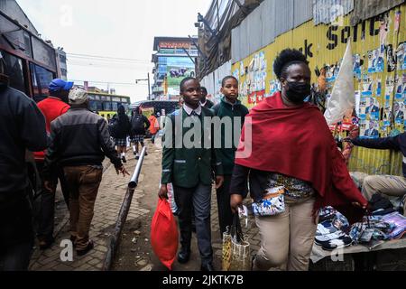 I pedoni e gli studenti camminano attraverso le trafficate strade del quartiere Centrale degli Affari di Nairobi mentre migliaia di studenti sono diretti per una breve pausa di tempo per Foto Stock