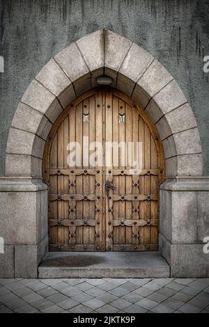 Arco in pietra con porte doppie in rovere con borchie in ferro per un classico look gotico. Foto Stock