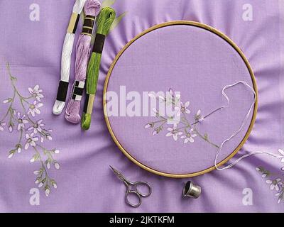 Cerchi in legno vintage da ricamo, forbici, ago, filo e tessuto con motivo piatto per ricamo a mano, vista dall'alto Foto Stock