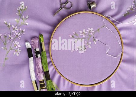 Cerchi in legno vintage da ricamo, forbici, ago, filo e tessuto con motivo piatto per ricamo a mano, vista dall'alto Foto Stock