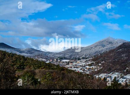 Una vista di un'area montagnosa all'inizio della primavera con piccole case sparse sotto il cielo blu Foto Stock
