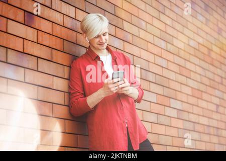 Uomo che utilizza un servizio di musica online. Giovane hipster con cuffie wireless. Foto Stock
