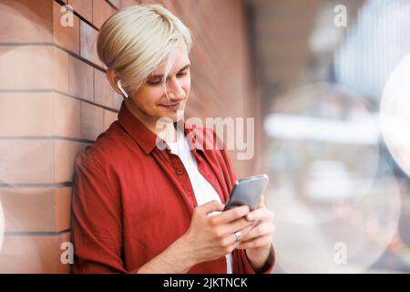 Uomo che utilizza un servizio di musica online. Giovane hipster con cuffie wireless. Foto Stock