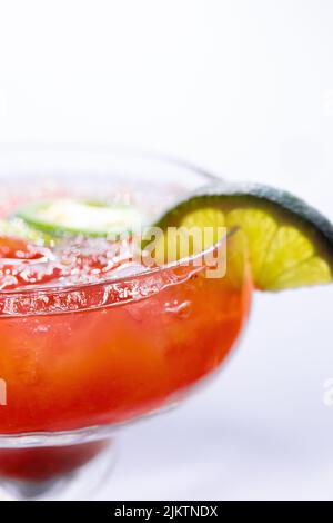 Un focus selettivo di una bevanda margarita rossa con lime e jalapeno su sfondo bianco Foto Stock